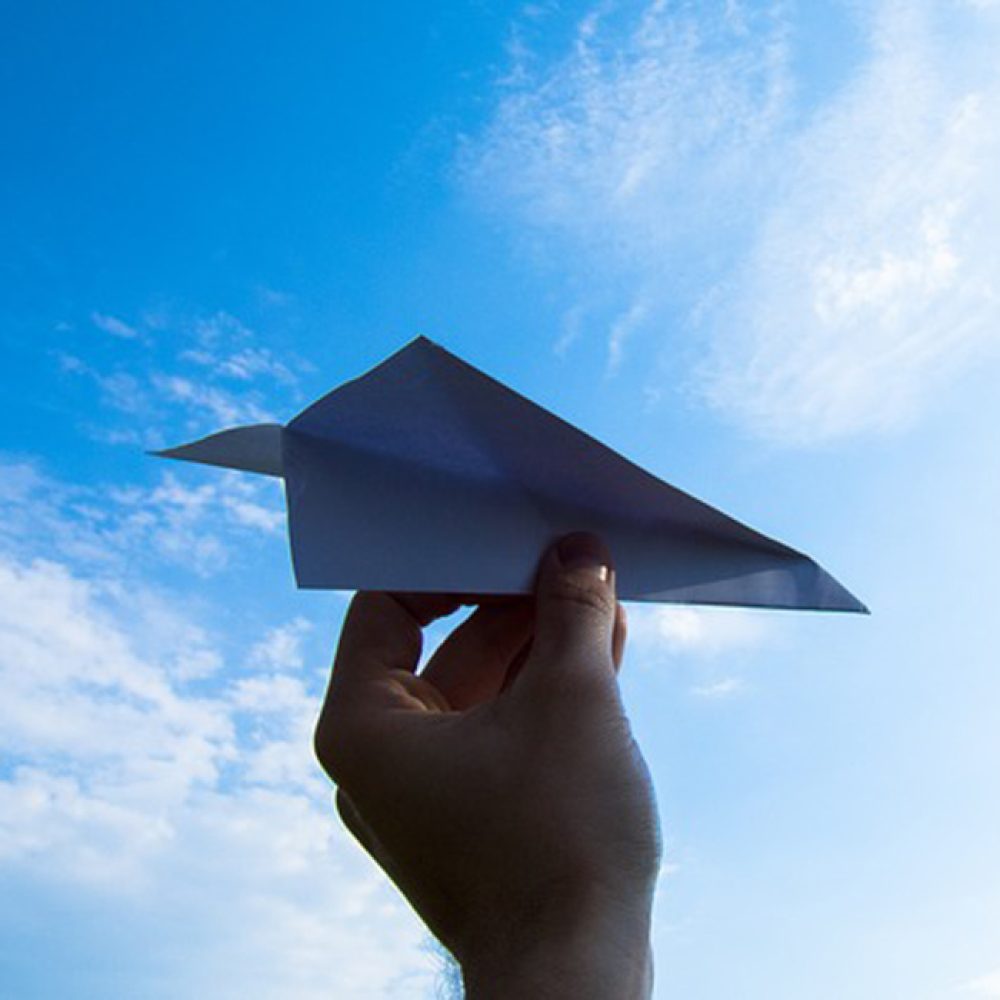 Papierflieger vor dem Himmel